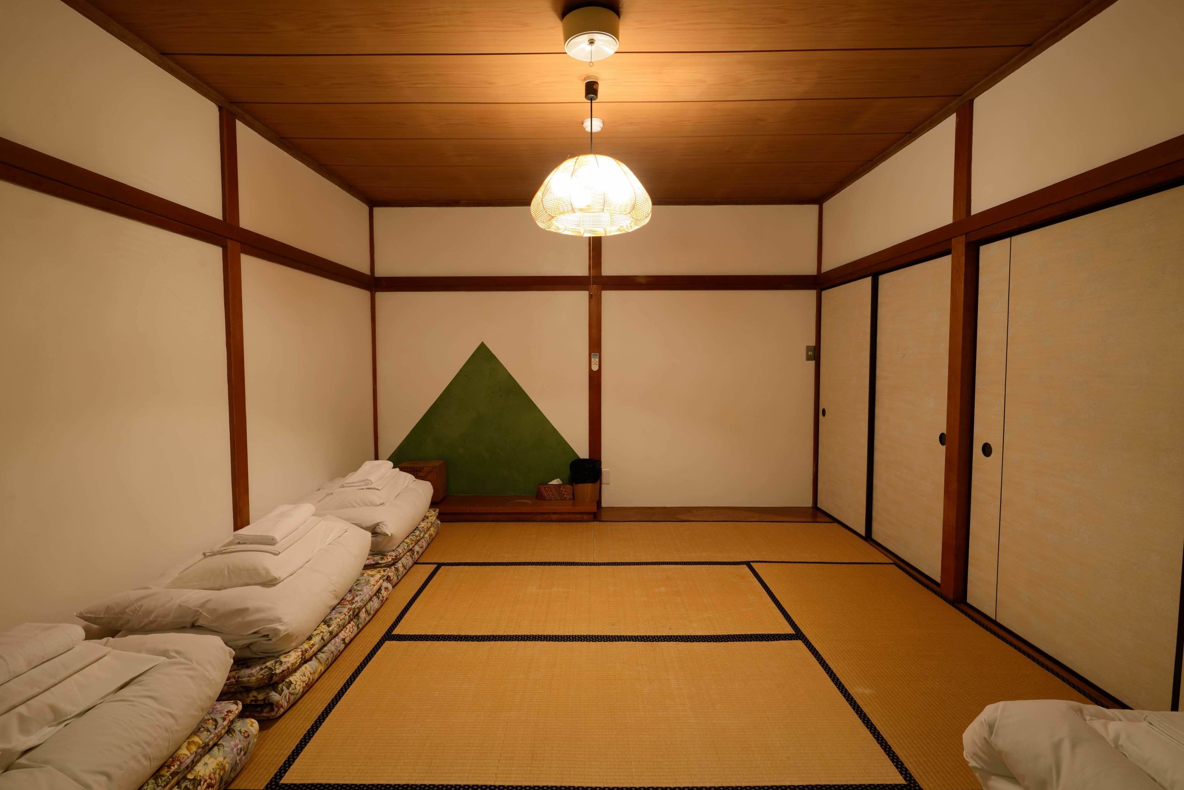 Ein traditioneller japanischer Raum mit Tatami-Böden, einer niedrigen Holzkονstruktion und einer hängenden Lampe.