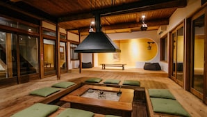 Quarto tradicional japonês, com tatames, mesas de madeira baixas e almofadas verdes.