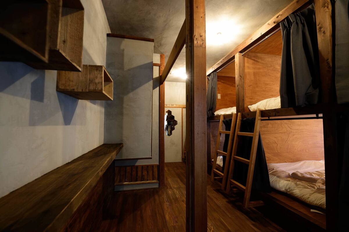 A narrow hallway with wooden bunk beds on one side and a wooden bench on the other.