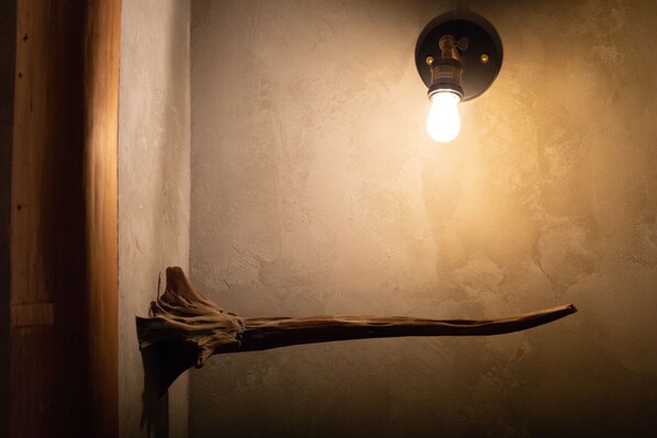 A wooden beam extending from a wall with a light fixture above it.