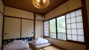 Um quarto japonês tradicional com tatames, biombos shoji e teto de madeira.