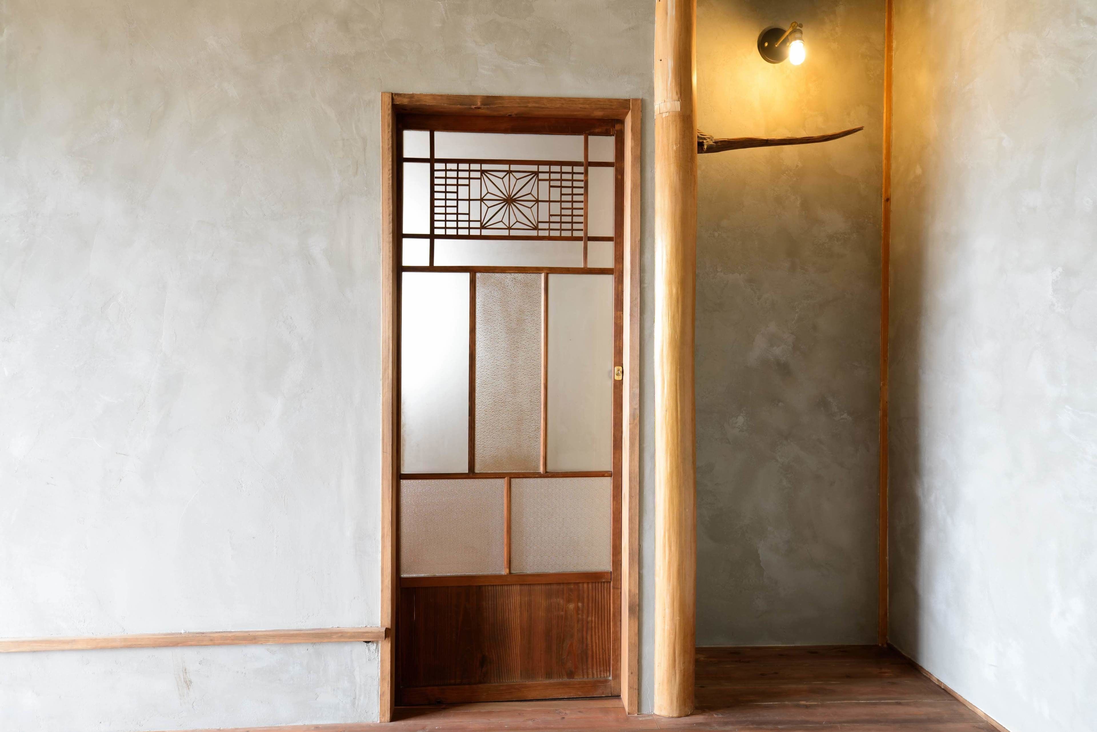 A traditional Japanese room with tatami flooring, a shoji screen door, and a wooden pillar.