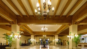 A spacious lobby with a grand chandelier, potted plants, and a central floral arrangement. - Club Solaris Los Cabos (San José del Cabo)