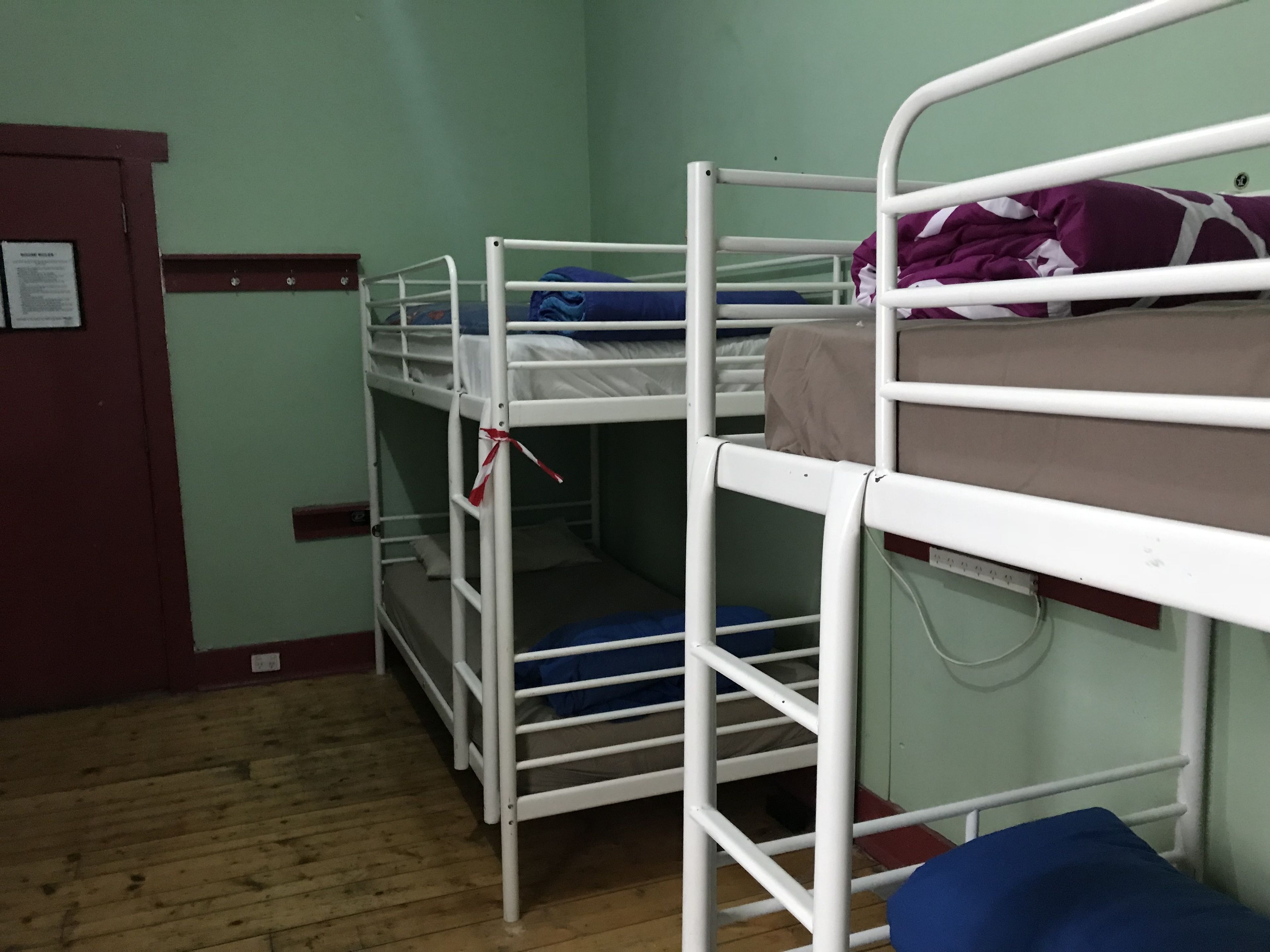A bunk bed room with a wooden floor and a door with a notice on it.