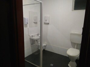 A small, compact bathroom with a glass shower enclosure, a white sink, and a toilet. - Market Tavern - Hostel and Bar (South Melbourne)