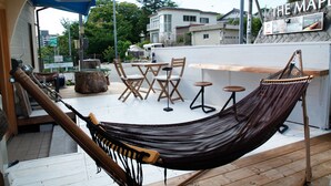 Una hamaca, sillas de madera, una mesita y una zona de bar en una terraza de madera.