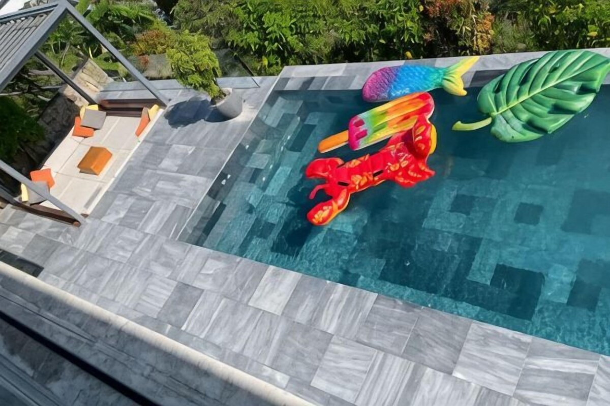 Une piscine agrémentée d’un jouet gonflable aux couleurs vives, d’un élément décoratif en forme de feuille et d’une terrasse carrelée.