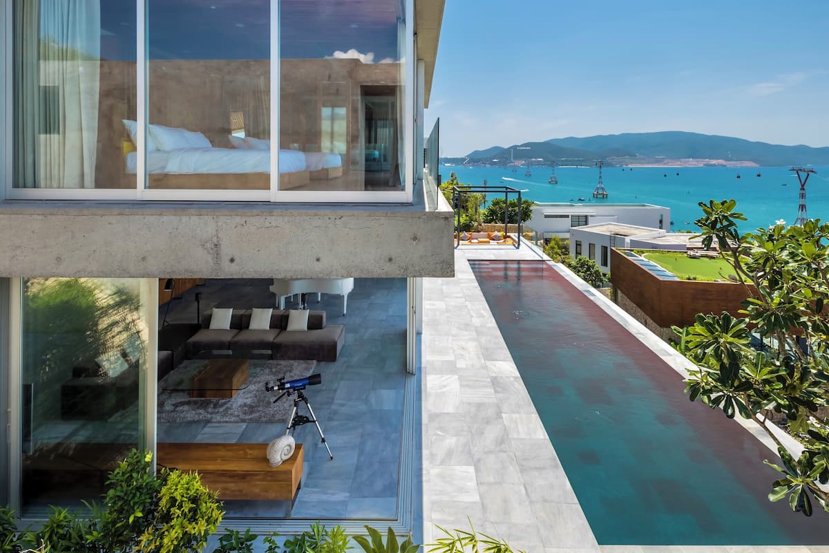 Un hôtel moderne doté d’un grand balcon en verre, d’une piscine et offrant une vue sur la mer.