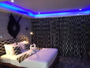 A modern hotel room with a bed, a wall-mounted light, and a decorative wall panel. - Fong Kaew and Baan Nang Fa Guesthouse (Patong)