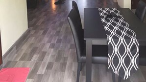 Ein modernes Wohnzimmer mit einer Couch, einem Esstisch mit Stühlen und einer gemusterten Tischläufer.