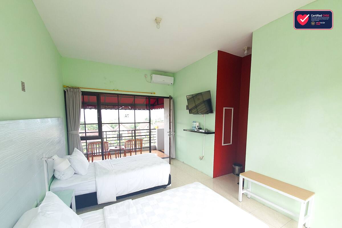 A hotel room with a bed, a bench, a TV, and a window with a view.