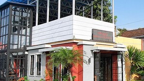 Un edificio de dos pisos con tejado azul, ventanas grandes y fachada roja y blanca.