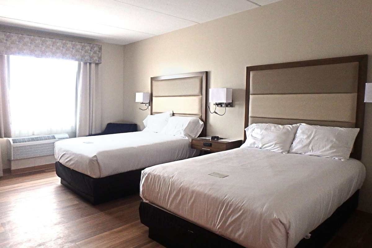 A hotel room with two beds, a desk, and a chair.