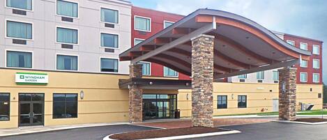 A Wyndham Garden hotel with a modern entrance, stone pillars, and a covered waiting area.