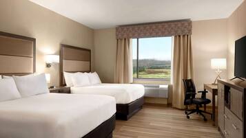 A hotel room with two beds, a desk, a chair, and a television.