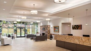 A spacious lobby with a reception desk, seating area, and large windows offering a view of the outdoors. - Wyndham Garden State College (Boalsburg)