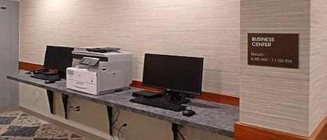A business center with a desktop computer, printer, and monitor.