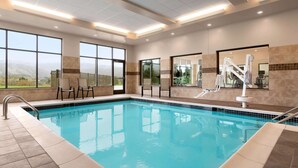 A swimming pool with clear blue water, large windows, and a view of the mountains. - Wyndham Garden State College (Boalsburg)