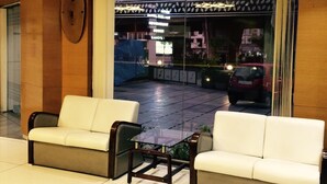 Un vestíbulo con dos sofás blancos y una mesa de centro de vidrio.