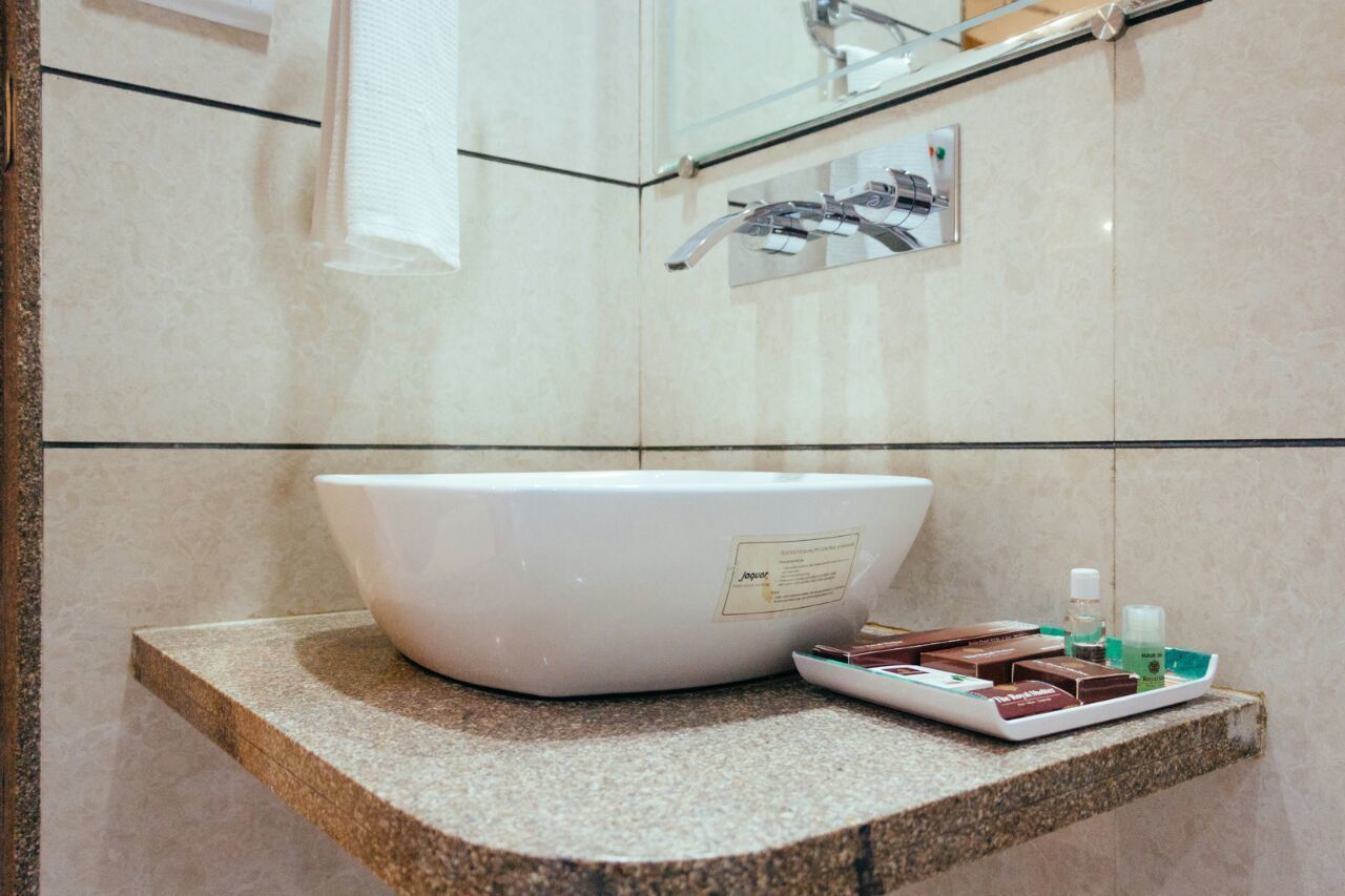 Een badkamer met een groot wit wastafelblad, een handdoekhouder en toiletartikelen op een schaal.