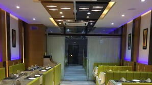Un restaurante con una decoración moderna, que presenta asientos tipo banca verdes y piso de baldosas.