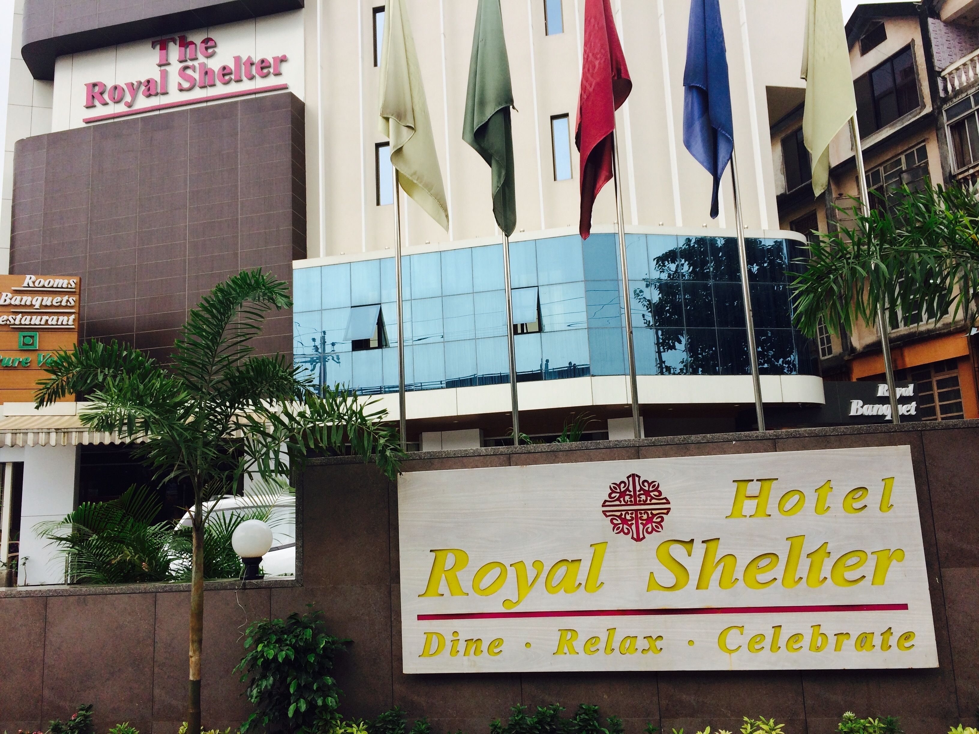 Un letrero de hotel con el nombre 'Royal Shelter' y el lema 'Comer · Relajarse · Celebrar'.