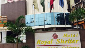 Un letrero de hotel con el nombre 'Royal Shelter' y el lema 'Comer · Relajarse · Celebrar'.