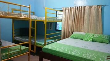 A dormitory room with bunk beds, a window with curtains, and a bed with green bedding.