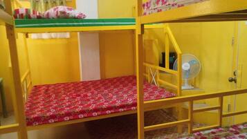 Dormitorio con literas, un ventilador y una puerta.