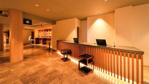 A reception area with a wooden reception desk, a laptop, and two bar stools. - Awazu-Spa Tourist Hotel Kitahachi (Komatsu)