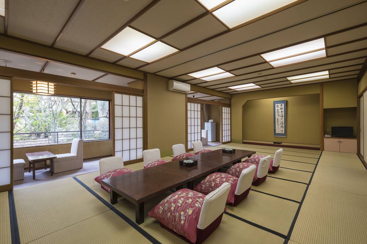 Une salle de réunion japonaise traditionnelle, avec des tatamis, une longue table en bois et des chaises blanches.