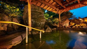 A tranquil indoor water feature with a wooden walkway and large rocks. - Awazu-Spa Tourist Hotel Kitahachi (Komatsu)