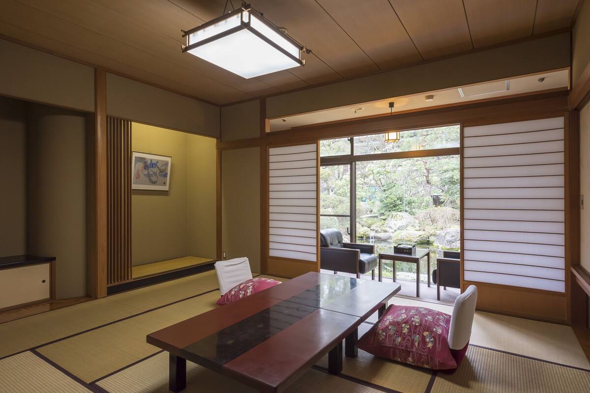 Une pièce de style japonais traditionnel, avec un sol recouvert de tatamis, une table basse et des portes coulissantes.