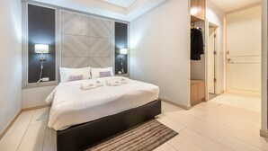 A modern bedroom with a large bed, bedside lamps, a wardrobe, and a view of the sky. - Visut House - Hostel (Bangkok)