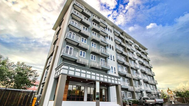 A multi-story residential building with balconies, a gated entrance, and a parking area. - Tai-Shan Suites (Ratchaburi)