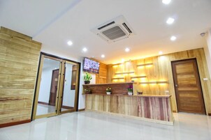 Un área de recepción con mostrador de madera, un televisor montado en la pared y un equipo de aire acondicionado instalado en el techo.