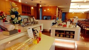 A buffet area with a variety of food items, including pastries and drinks, in a well-lit room with wooden flooring and a central island. - Tai-Shan Suites (Ratchaburi)