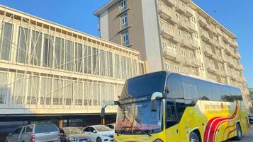 A yellow and red bus parked in front of a building with multiple balconies.