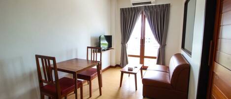 A compact living space with a dining table, chairs, a sofa, and a television.