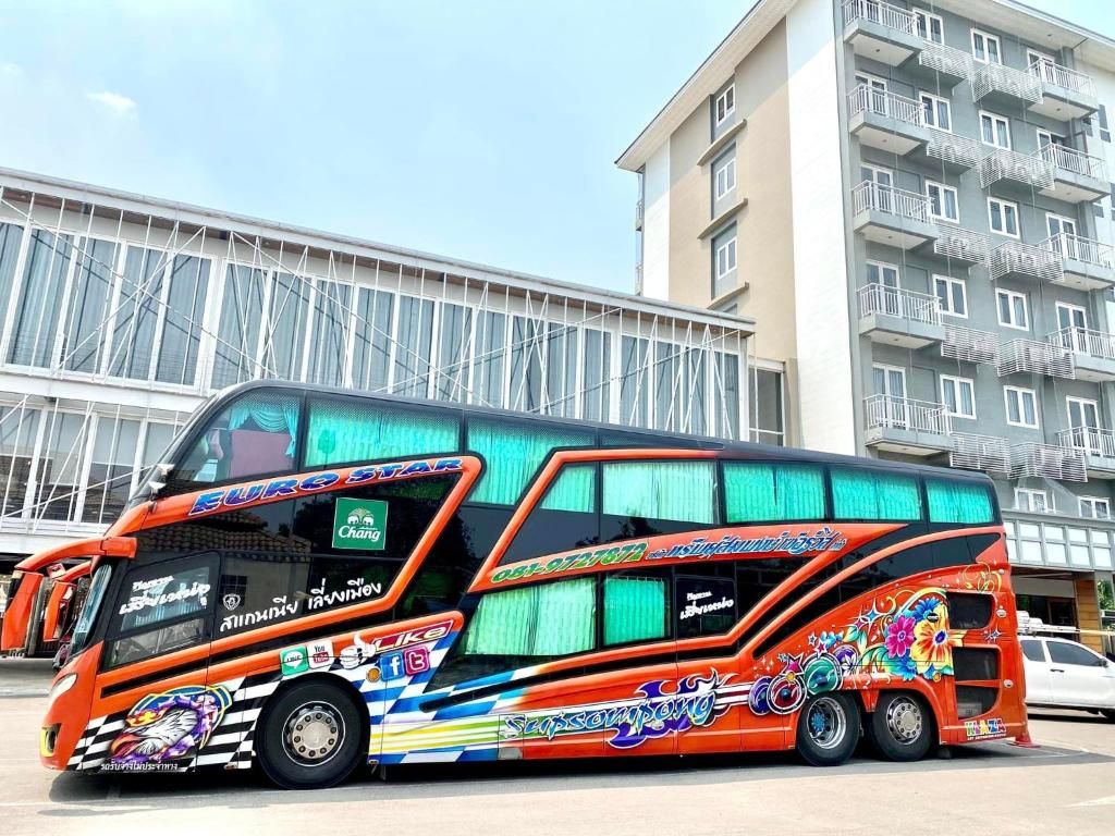 Un autobús de dos pisos con gráficos coloridos estacionado frente a un edificio.