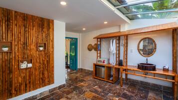 Une salle de bain moderne avec un mur en bois, un plafond en verre, un banc en bois, un lavabo et un miroir.