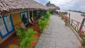 A terrace with thatched-roof huts, potted plants, and a tiled walkway.