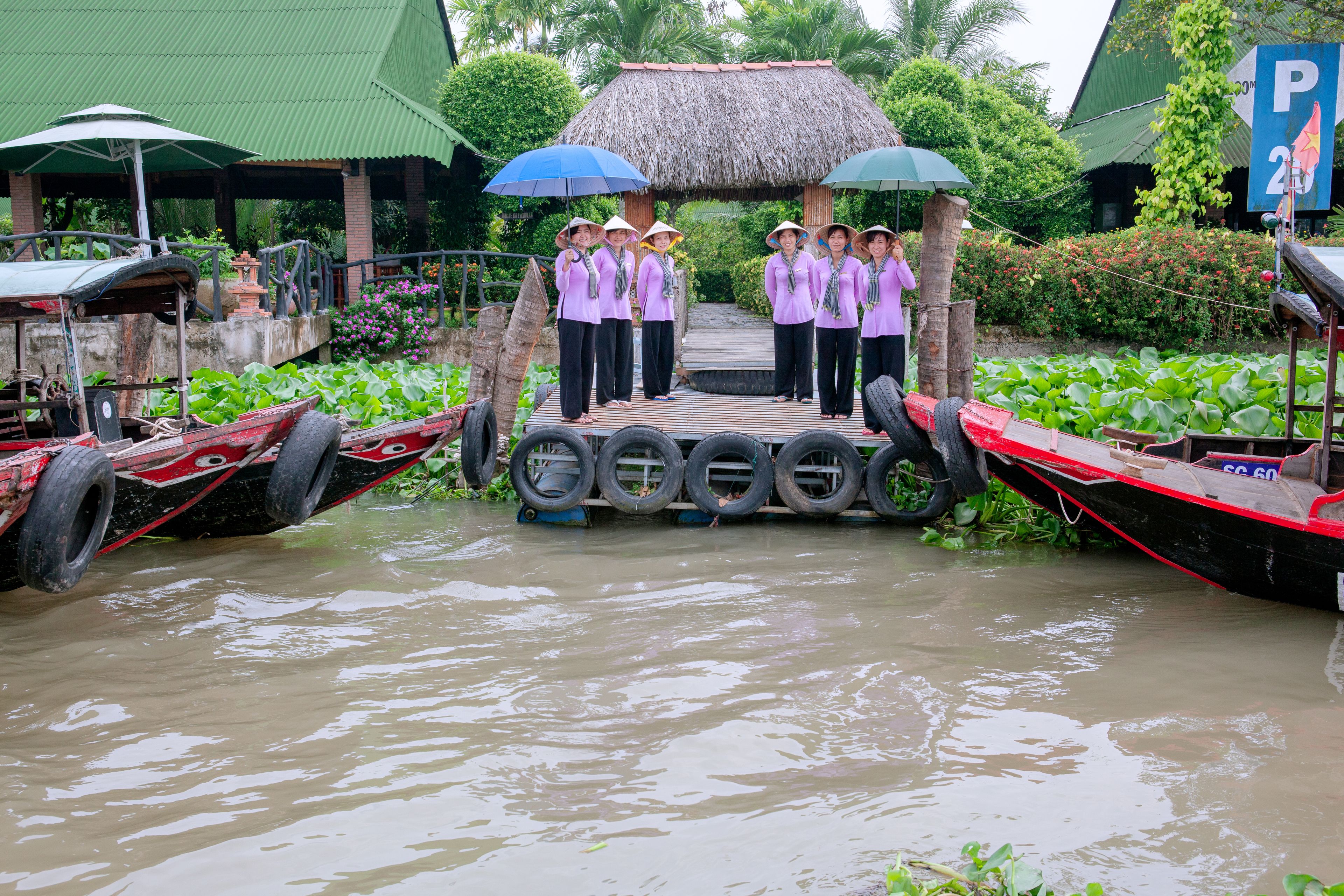 A group of people standing on a platform with tires, surrounded by water and boats.
