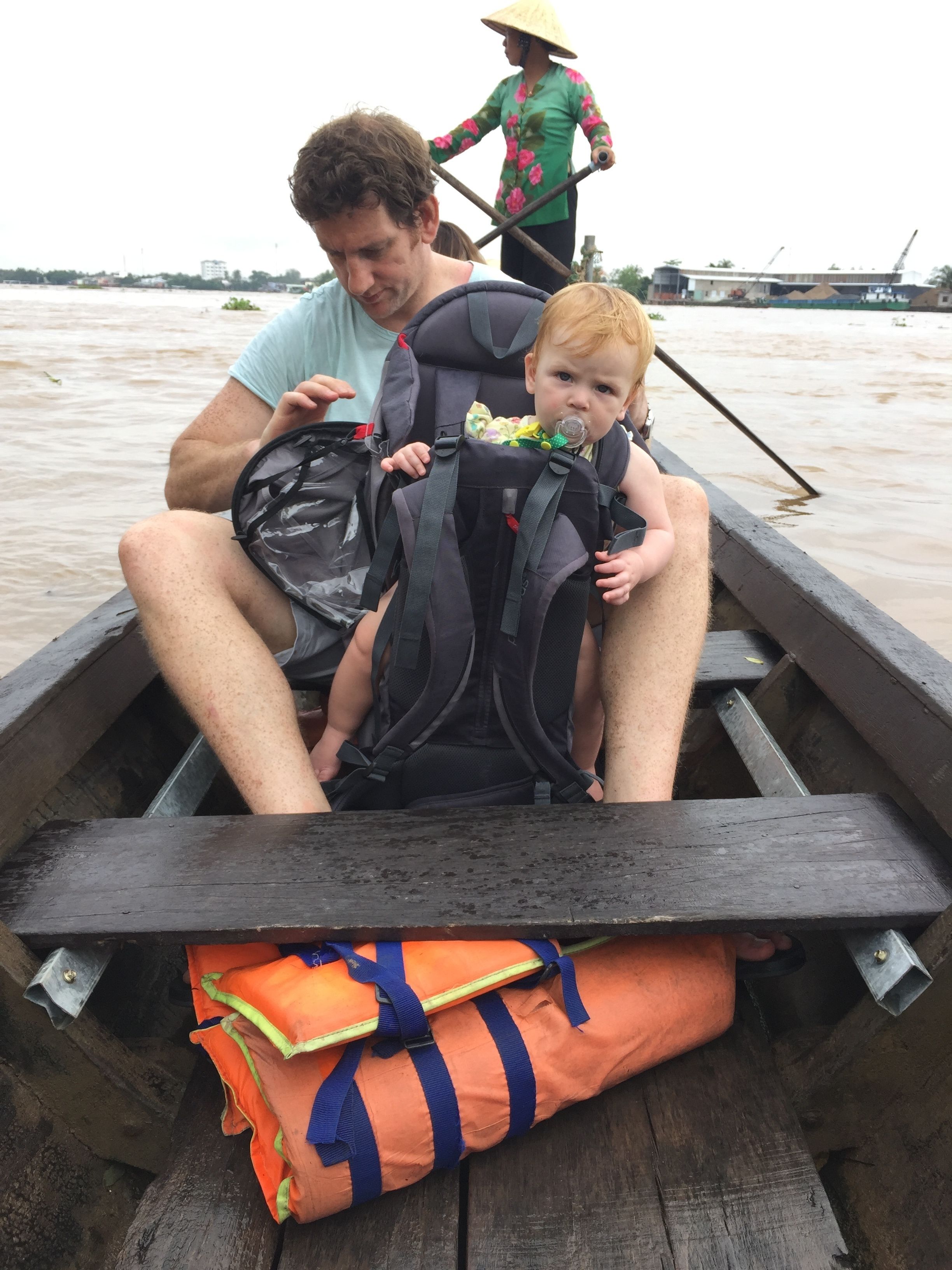 Un hombre y un niño en un bote, con chaleco salvavidas y una bolsa.