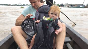 Un hombre y un niño en un bote, con chaleco salvavidas y una bolsa.