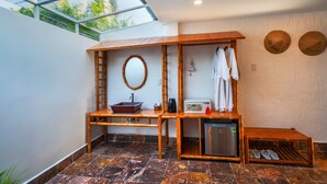 A bathroom with a wooden vanity, a sink, a mirror, a towel rack, and a shower area. - Mekong Lodge Hotel & Resort (Cai Be)