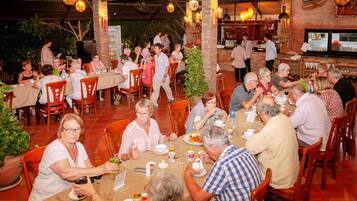 Un restaurante con terraza, paredes de ladrillo y luces colgantes.