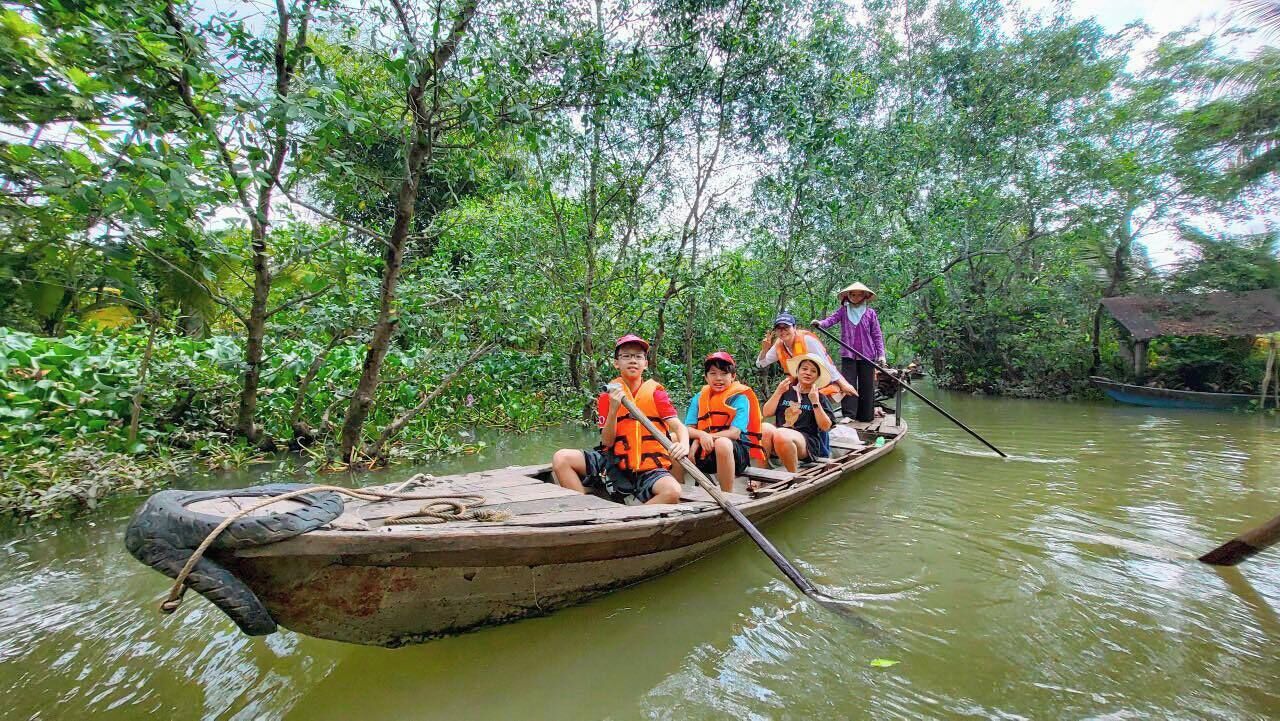 A group of people in a small wooden boat on a river surrounded by dense greenery.