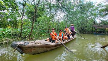 A group of people in a small wooden boat on a river surrounded by dense greenery.