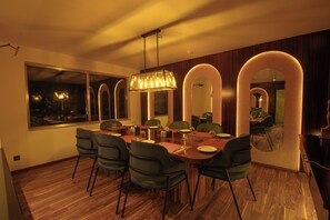 A modern dining area with a wooden table, green chairs, and a pendant light. - Hotel Le Himalaya by Best Resort Nepal (Kathmandu)